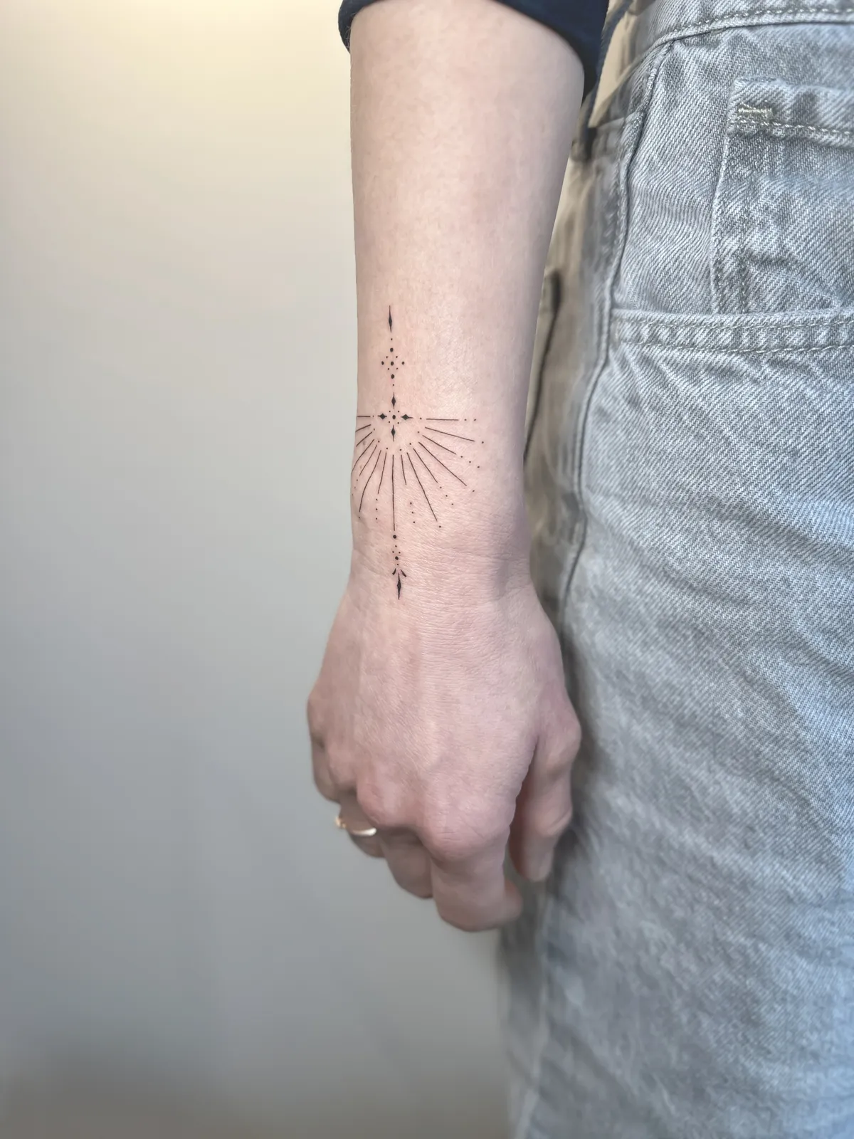 Tatuagem fineline de raios de sol no pulso
