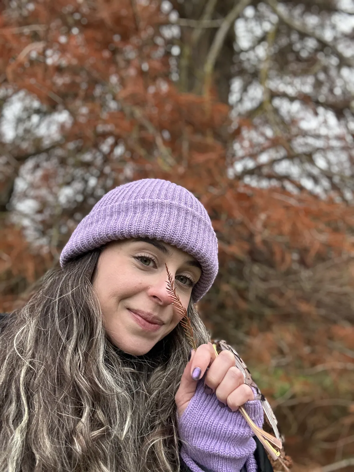 Talita de gorro lil&aacute;s entre folhas de outono